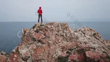 一个女孩站在海边的悬崖边上。 无人机的空中射击。 贝加尔湖。